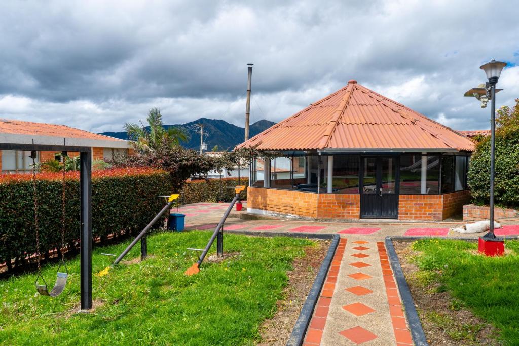 a gazebo with a building with a red roof at Hotel Centro Recreacional Villa El Encanto in Belén