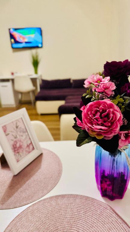 a vase filled with pink flowers sitting on a table at SHoliday Parter Clădire Nouă Spațiu Modern & Parcare Privată in Dumbrăviţa