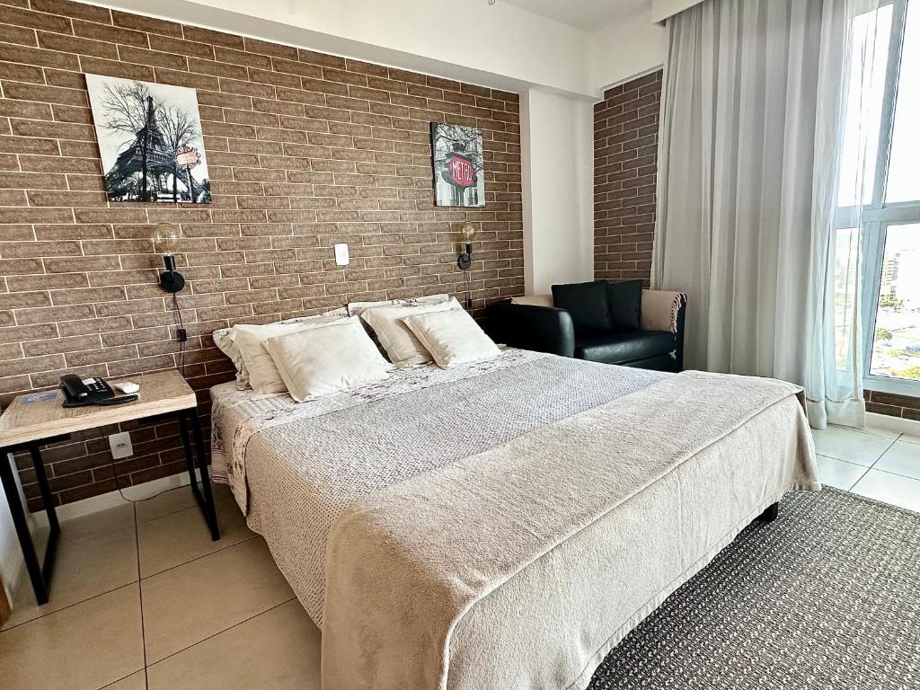 a bedroom with a large bed and a brick wall at Ed Saint Moritz, Flat 02 com Garagem, SHN no Coração de Brasília in Brasilia
