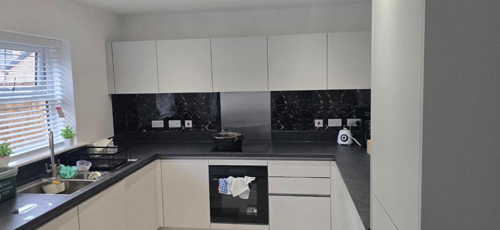 ハルにあるLovely accomodation with free parking & WiFiの白いキャビネットと黒いカウンタートップを備えたキッチン