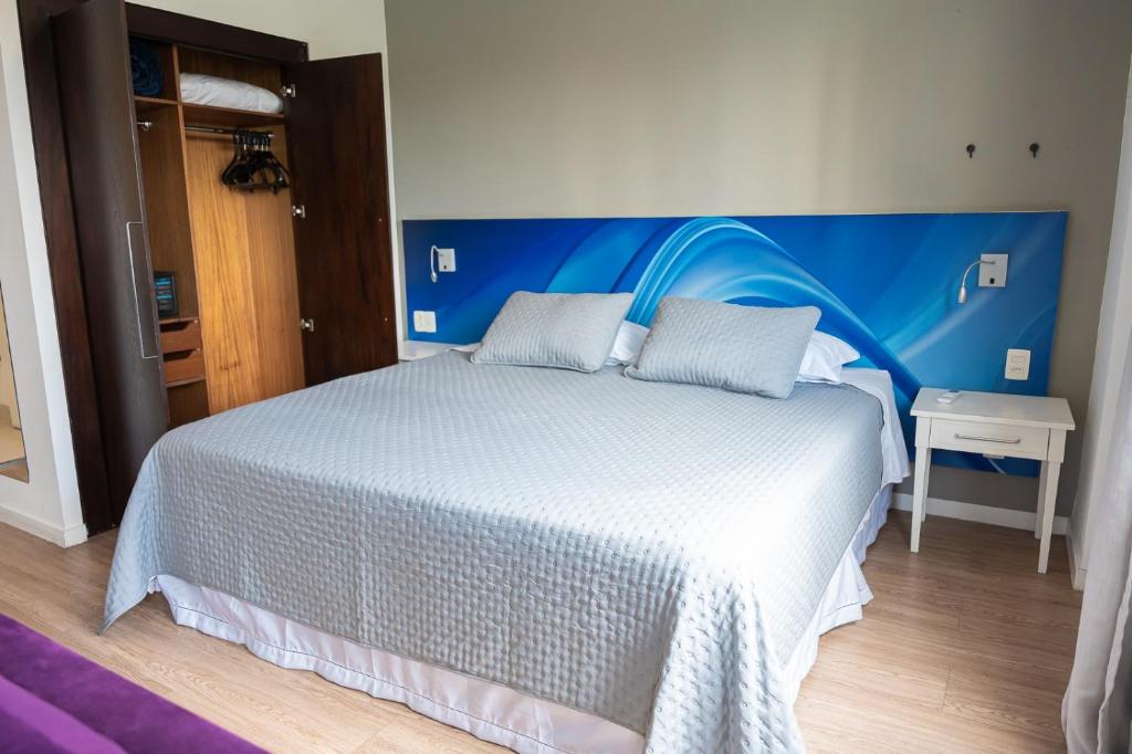 a bedroom with a large bed with a blue headboard at Prime Flat - Metrópolis Alphaville in Barueri