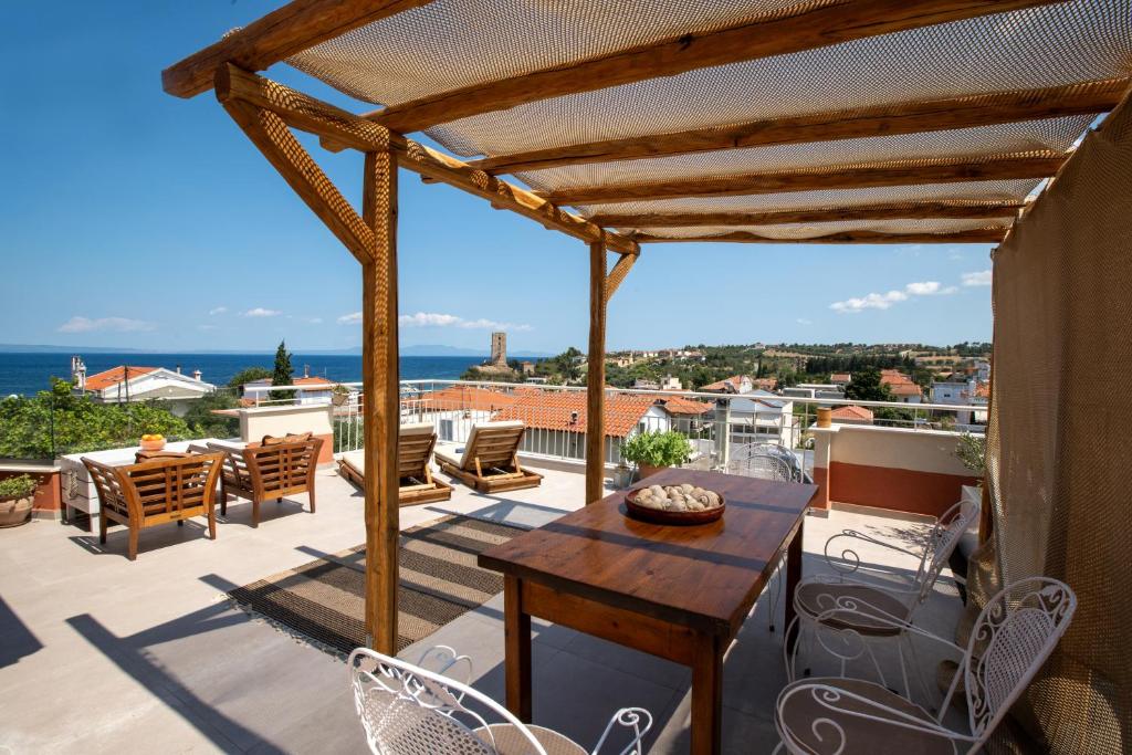 a patio with a wooden table and chairs on a balcony at Delmare Tower View Suites in Nea Fokea