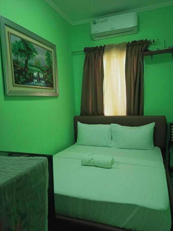 a green bedroom with a bed and a window at 2 - Cabanatuan City’s Best Bed and Breakfast Place in Cabanatuan