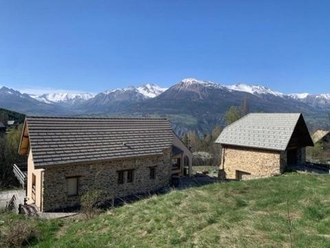 deux bâtiments sur une colline avec des montagnes en arrière-plan dans l'établissement Grande maison, calme et montagnes, à Crots