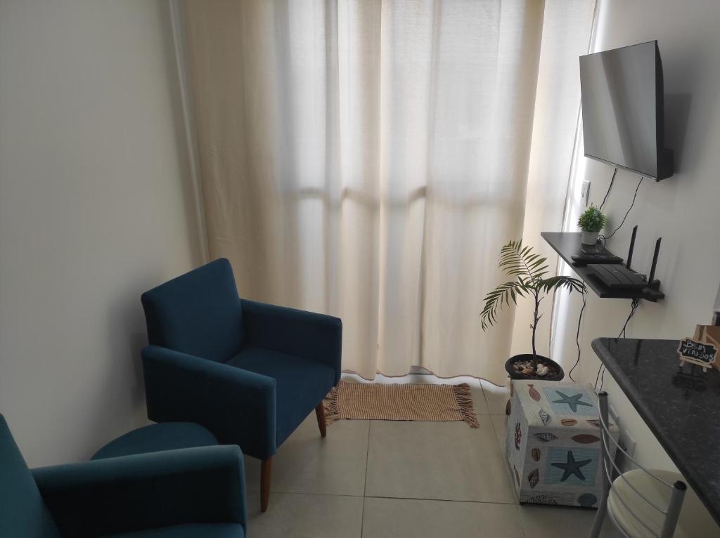 a living room with a blue chair and a television at Apt no Santa Mônica próximo ao Pátio Sabiá, UFU in Uberlândia