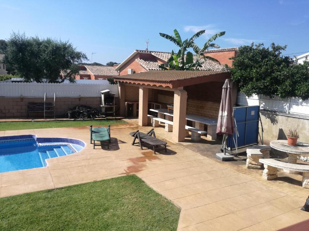 a backyard with a pool and a table and an umbrella at casa con piscina Comarruga in Comarruga