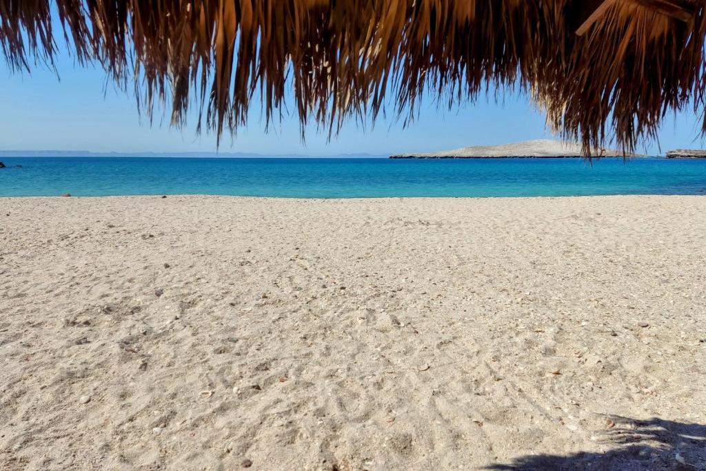 a beach with footprints in the sand and the ocean at Econo Beach Cantamar in La Paz