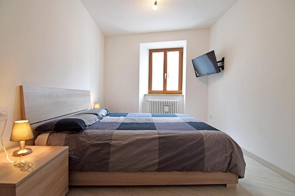 a bedroom with a bed and a tv on a wall at Casa Angelini in Castello di Fiemme