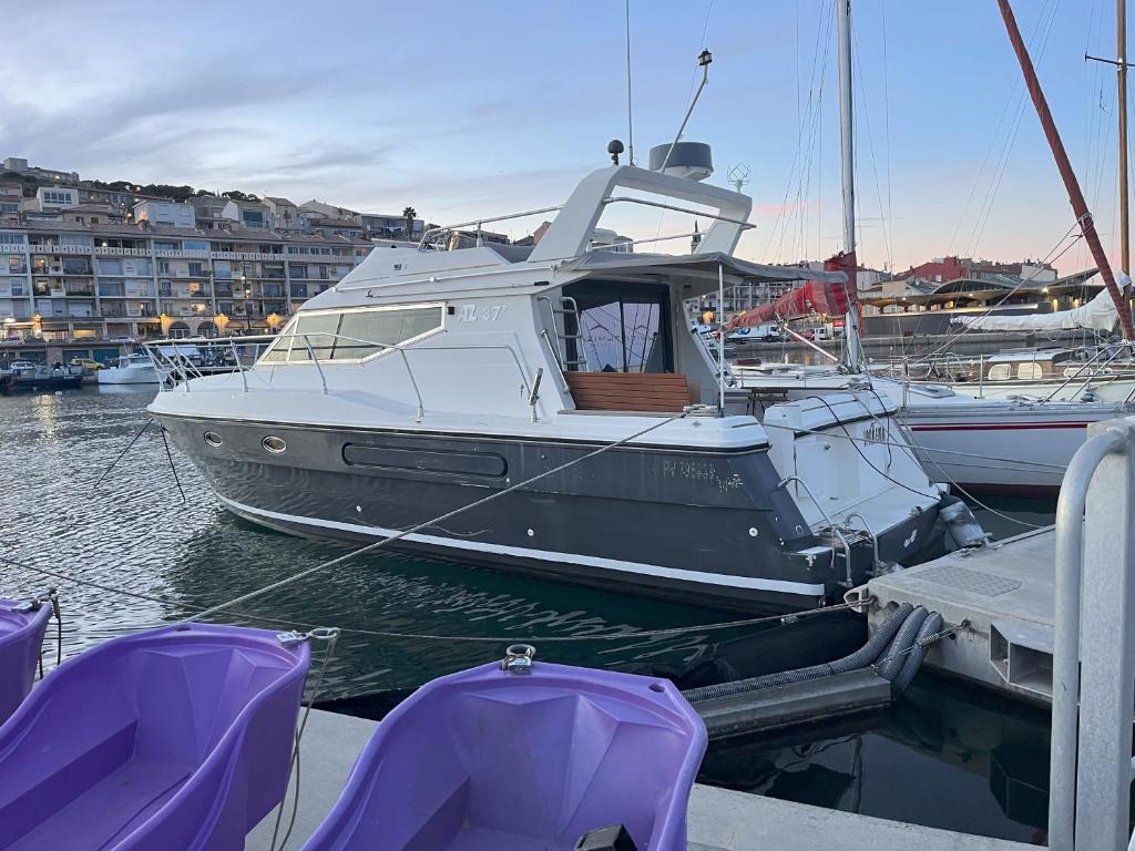 a boat is docked at a marina with purple seats at IPANEMA - JOLI BATEAU à QUAI in Sète
