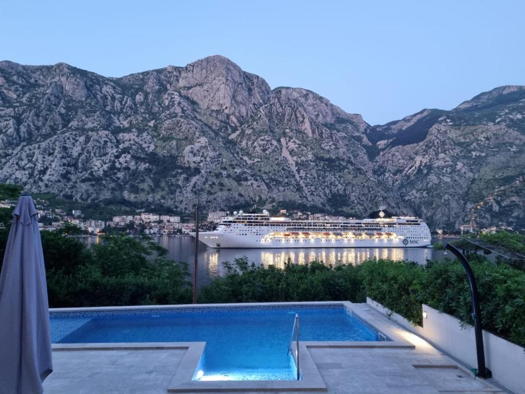 un navire de croisière dans une masse d'eau avec des montagnes dans l'établissement Sea view apartment with heated pool, à Kotor