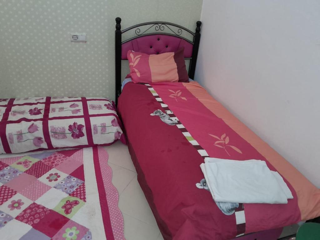 a bedroom with a bed with pink and white sheets at شقة in Selouane