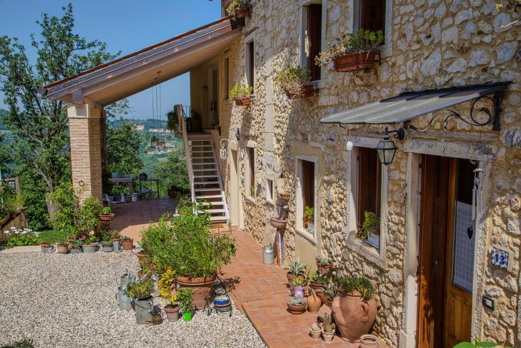 a stone house with a courtyard with potted plants at Ai due Gelsi in Grancona