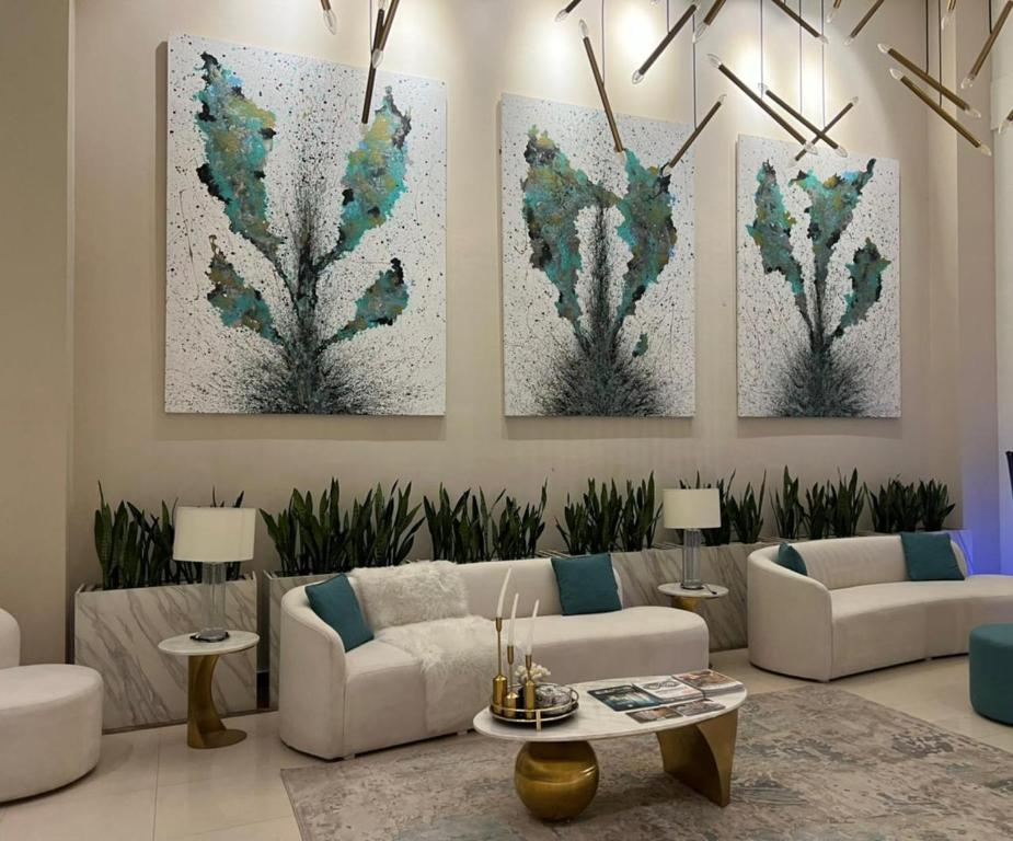 a living room with three paintings on the wall at Luxor Apartments & Suites - Opal in Lahore