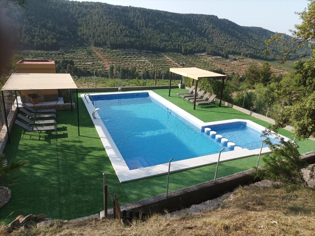 a swimming pool in a field with a mountain in the background at Casas Rurales Ivan El Penas in Benizar
