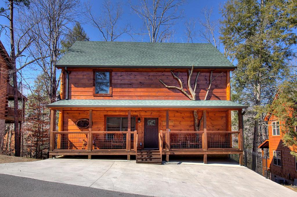 a log cabin with a porch and a house at Pebblestone Lodge in Pigeon Forge