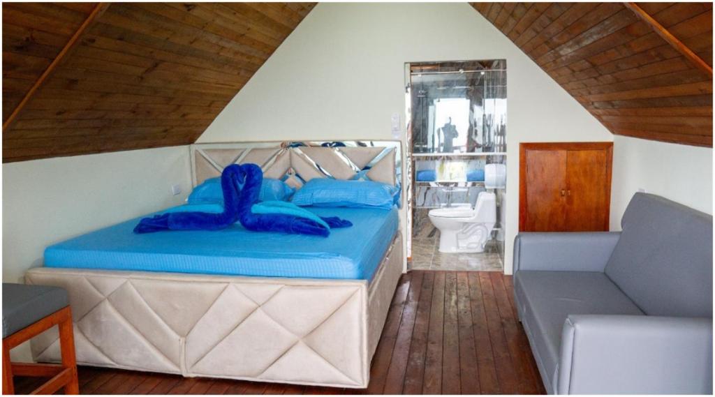 a bedroom with a bed with blue pillows on it at Hostal Sierra Minca in Minca