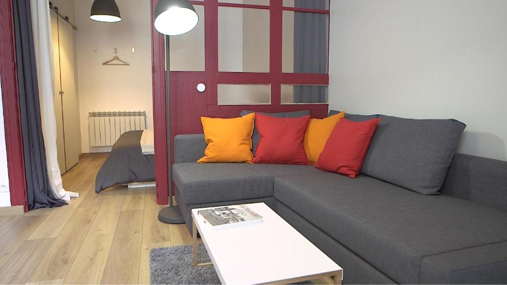 uma sala de estar com um sofá cinzento com almofadas coloridas em Les Rochelais 12B em La Rochelle