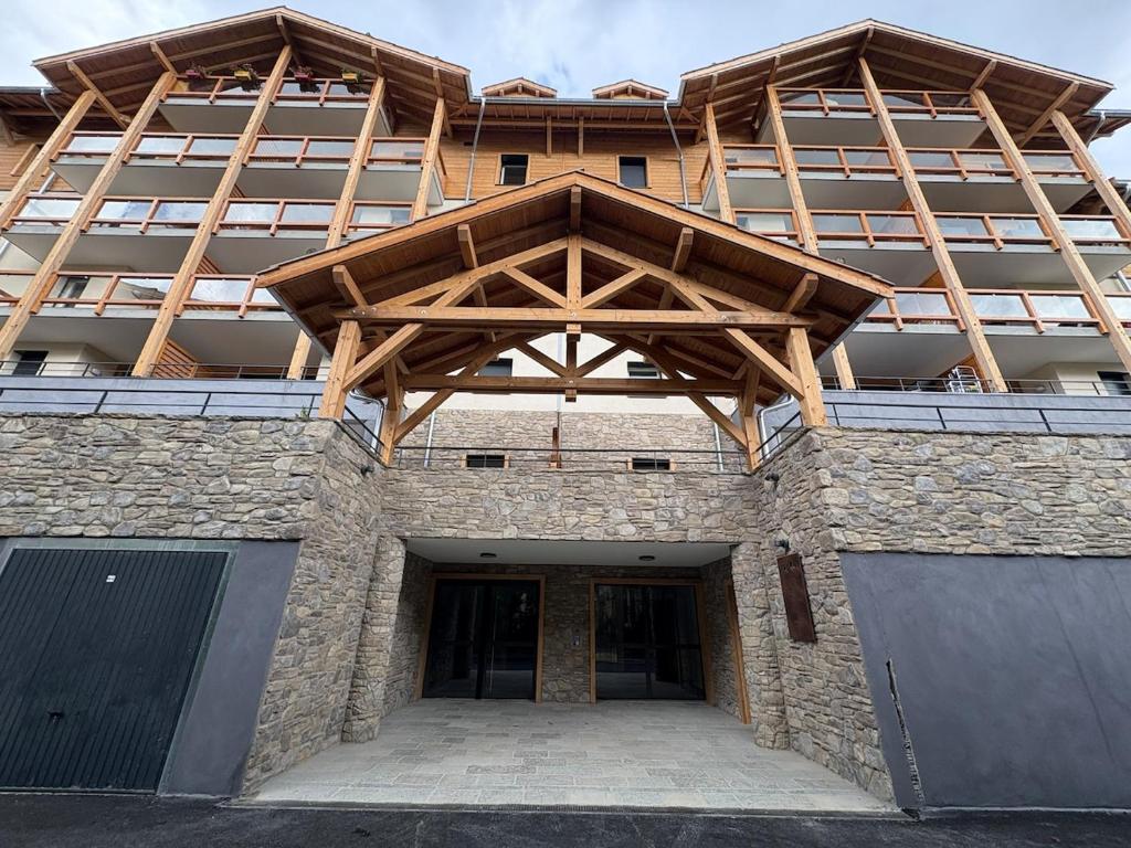 - un grand bâtiment avec un toit en bois dans l'établissement Briançon au pied des pistes, à Briançon