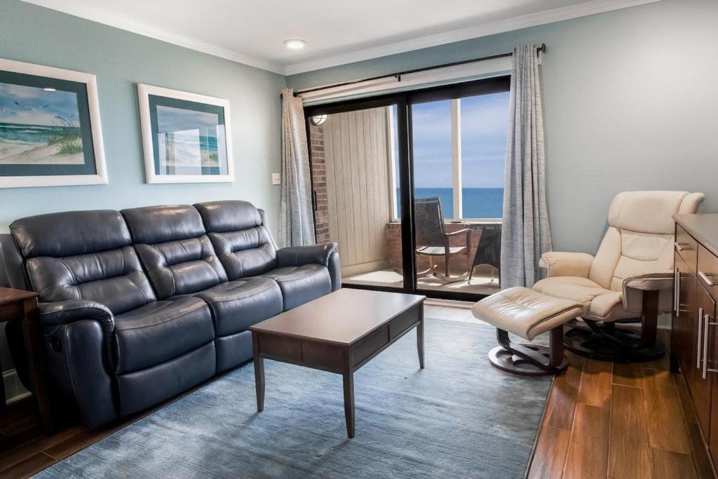 a living room with a leather couch and a chair at Beautiful Oceanfront 2 Bedroom Villa 2nd Floor in Pawleys Island