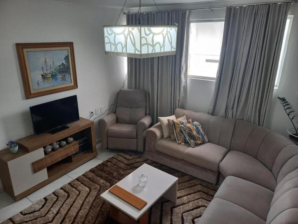 a living room with a couch and a tv at Apartamento Indianópolis in Caruaru