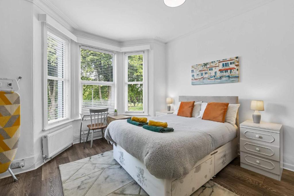a white bedroom with a large bed and windows at 4 Bed Park View House-Free Parking - Sleep 8 in Plymouth