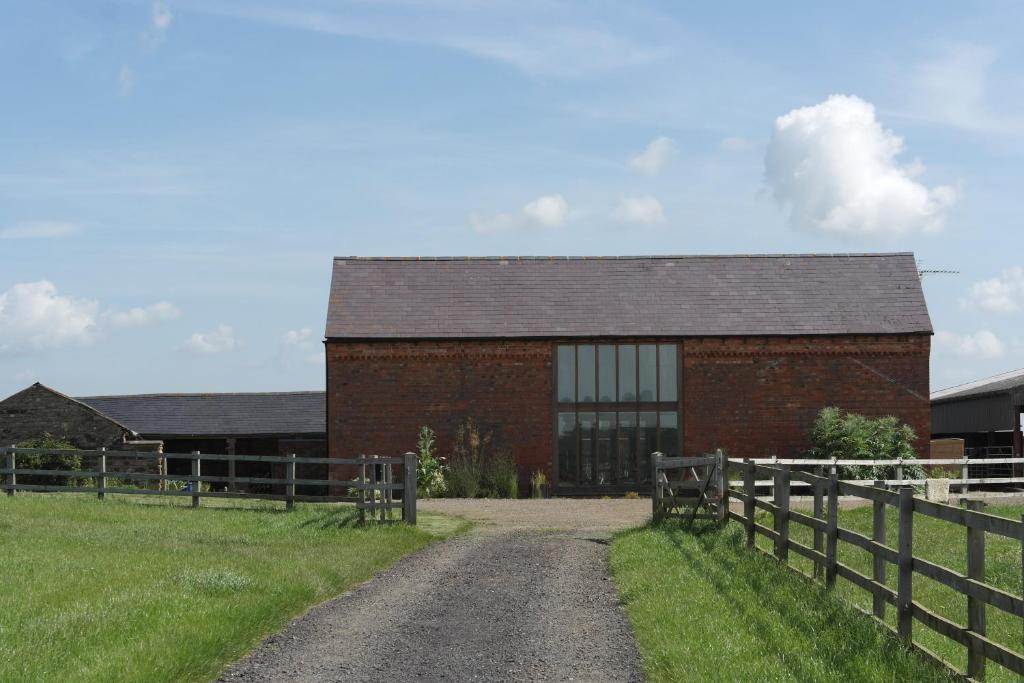 een bakstenen gebouw met een hek naast een onverharde weg bij Handley Barn in Silverstone