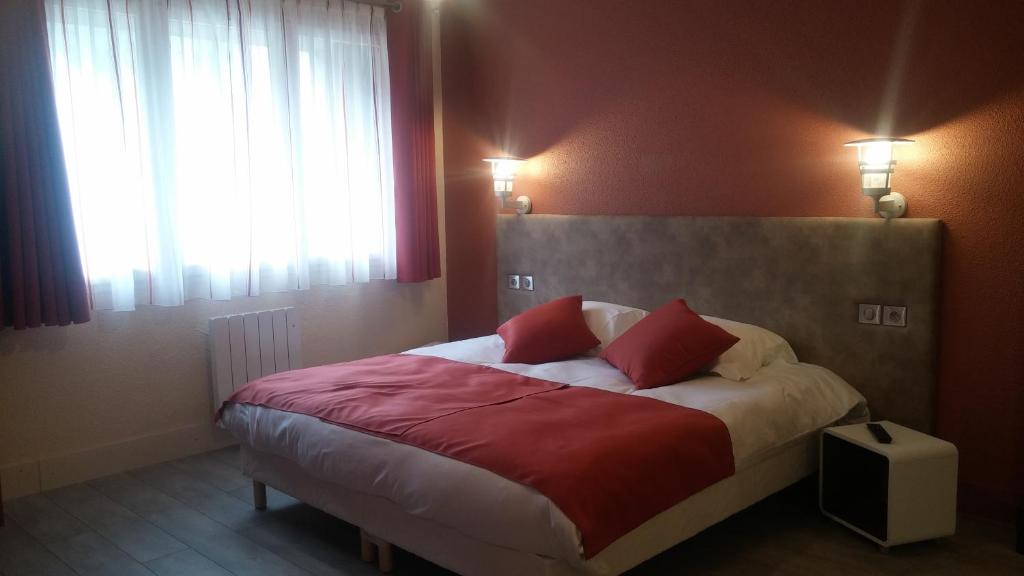 - une chambre avec un lit et 2 oreillers rouges dans l'établissement Oyonnax Bellignat Appart Hotel, à Bellignat