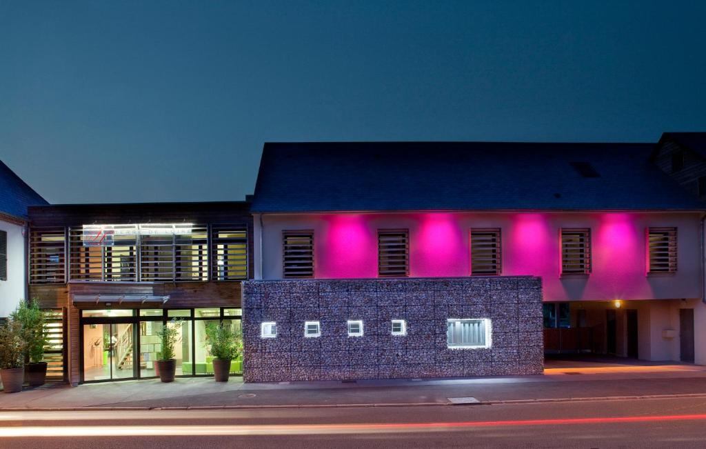 un edificio con luces rosas en el lateral. en Logis Hôtel Terre de Loire, en Belleville-sur-Loire