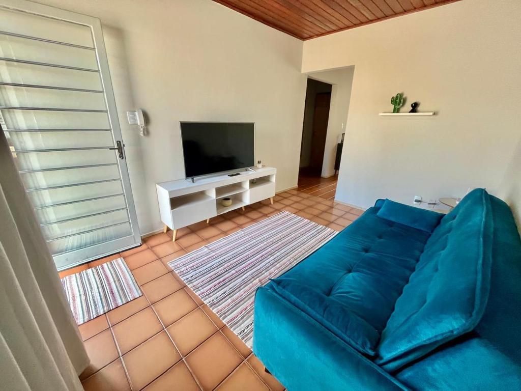 a living room with a blue couch and a television at Casa em Condomínio no Centro de Ponta Porã in Ponta Porã