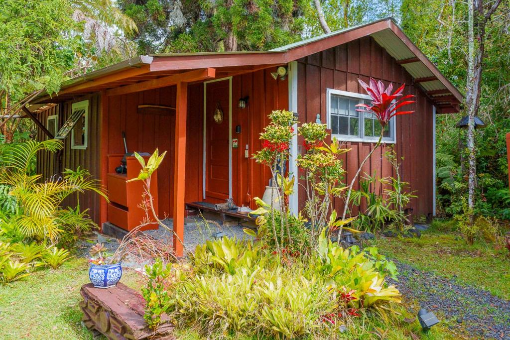 a small red shed with a porch in a garden at Volcano Artist Cottage in Volcano