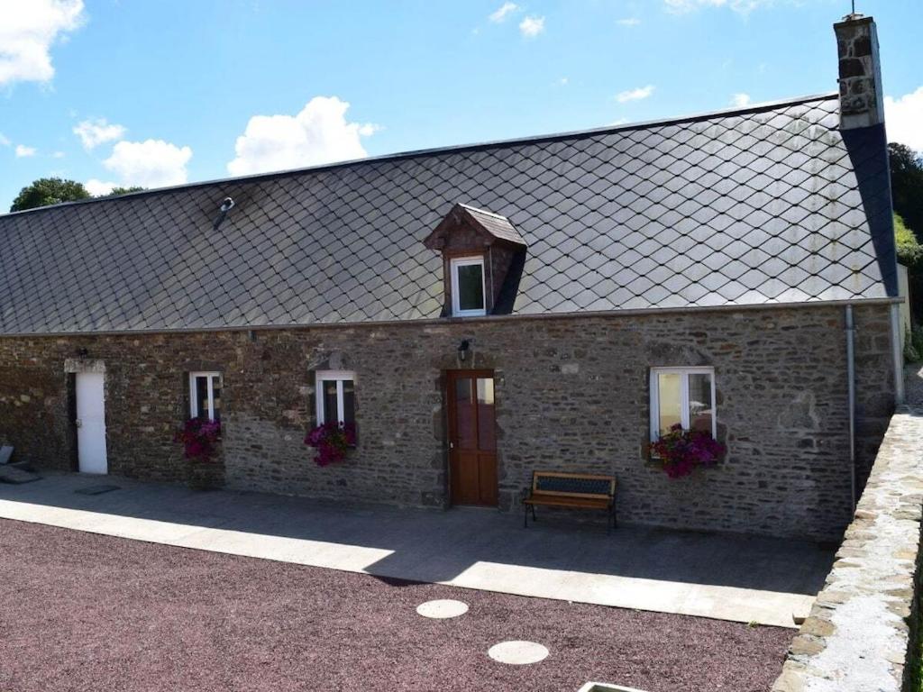 un bâtiment en briques avec une porte rouge et un banc dans l'établissement Holiday cottage with 2 bedrooms, à Saint-Lo-dʼOurville