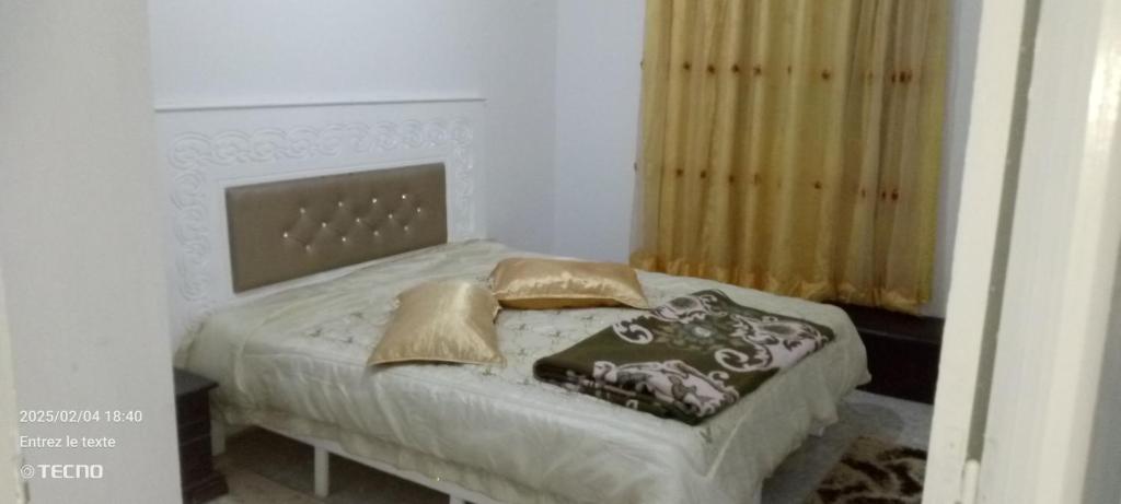 ein kleines Schlafzimmer mit einem Bett mit goldenen Kissen in der Unterkunft Dar MORTADA TATAOUINE in Tataouine