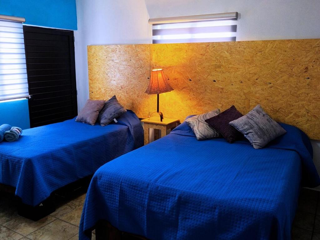 two beds in a room with blue sheets and a lamp at Nuevo Depa Turquesa chic y súper cómodo in Ciudad Victoria