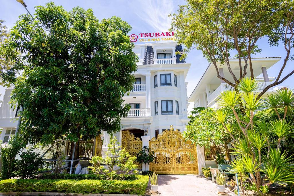 a white building with a gate and trees at TSUBAKI VILLA nha trang in Nha Trang