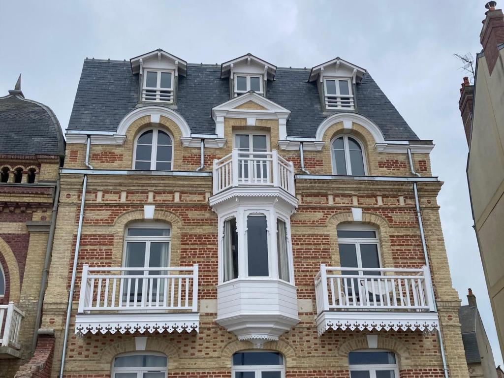 duży ceglany budynek z białym balkonem w obiekcie Appartement en front de mer à Villers-sur-Mer face au Casino, 2P tout équipé avec parking privatif - FR-1-712-14 w mieście Villers-sur-Mer