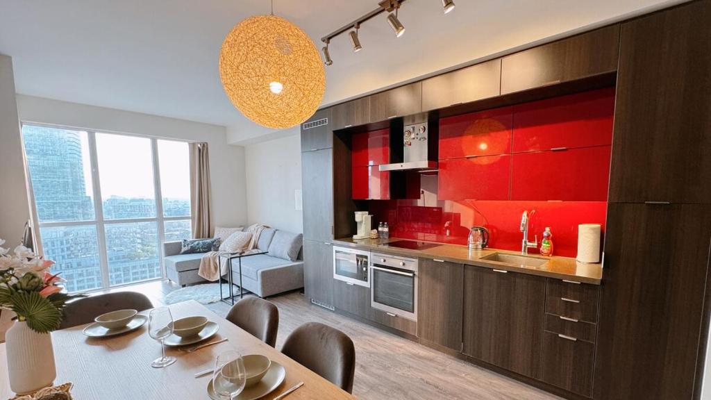 a kitchen with red cabinets and a table with chairs at Luxury 1 BR and Den Near CN Tower in Toronto