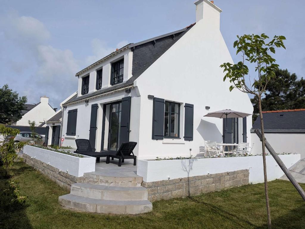 une maison blanche avec un banc et un parasol dans l'établissement Saint-Pierre-Quiberon - Villa spacieuse 9 pièces, 14 pers., grand jardin - FR-1-478-319, à Saint-Pierre-Quiberon