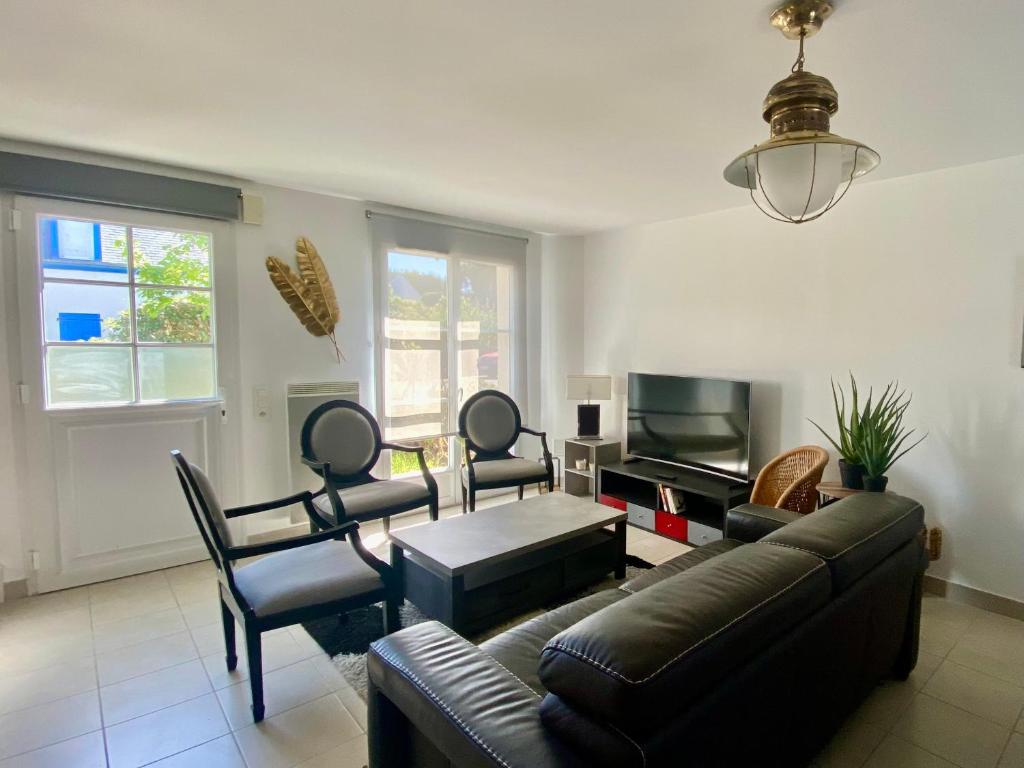 un salon avec un canapé, des chaises et une télévision dans l'établissement Maison rénovée proche du bourg avec terrasse et jardin - FR-1-813-26, à Groix