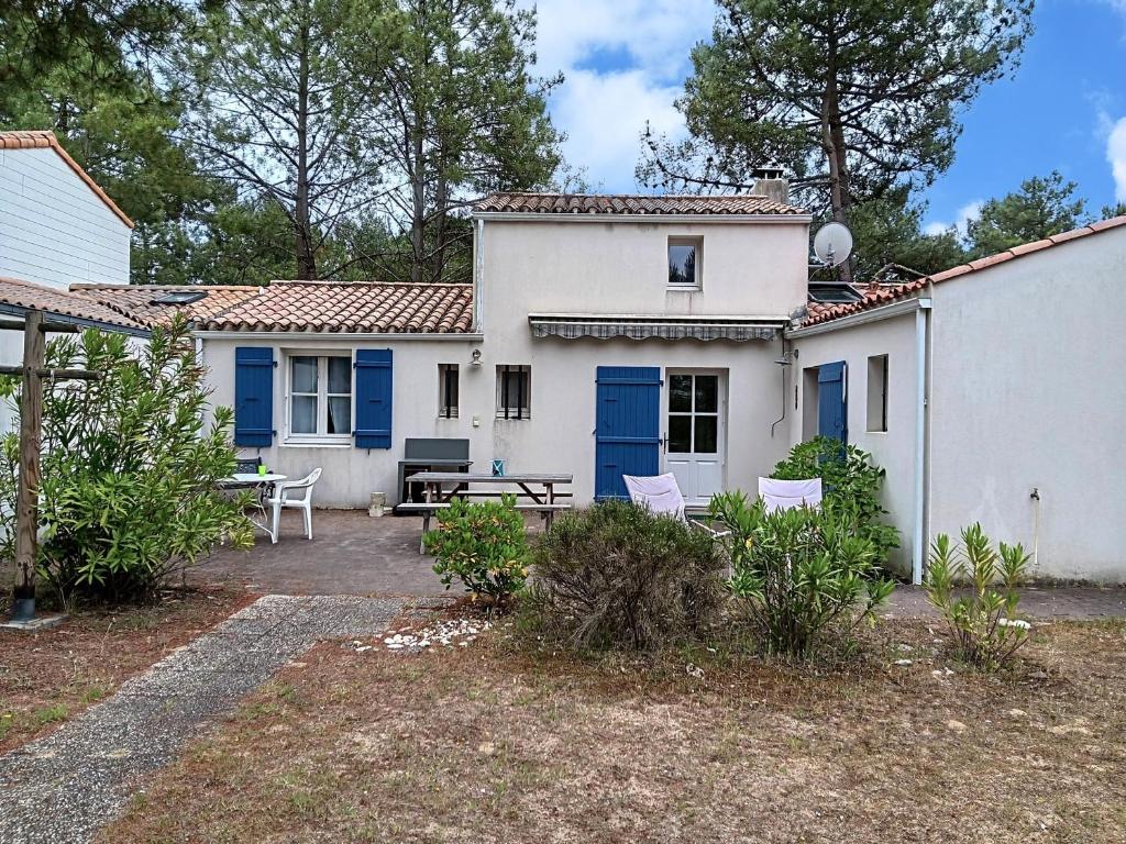Cette maison blanche dispose de portes bleues et d'une terrasse. dans l'établissement Maison 4 chambres près plage, forêt, wifi, 8 pers - FR-1-476-241, à La Faute-sur-Mer