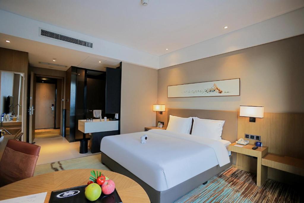 a hotel room with a large white bed and a table at Holiday Inn Express Chengdu Wenjiang Hotspring by IHG in Chengdu