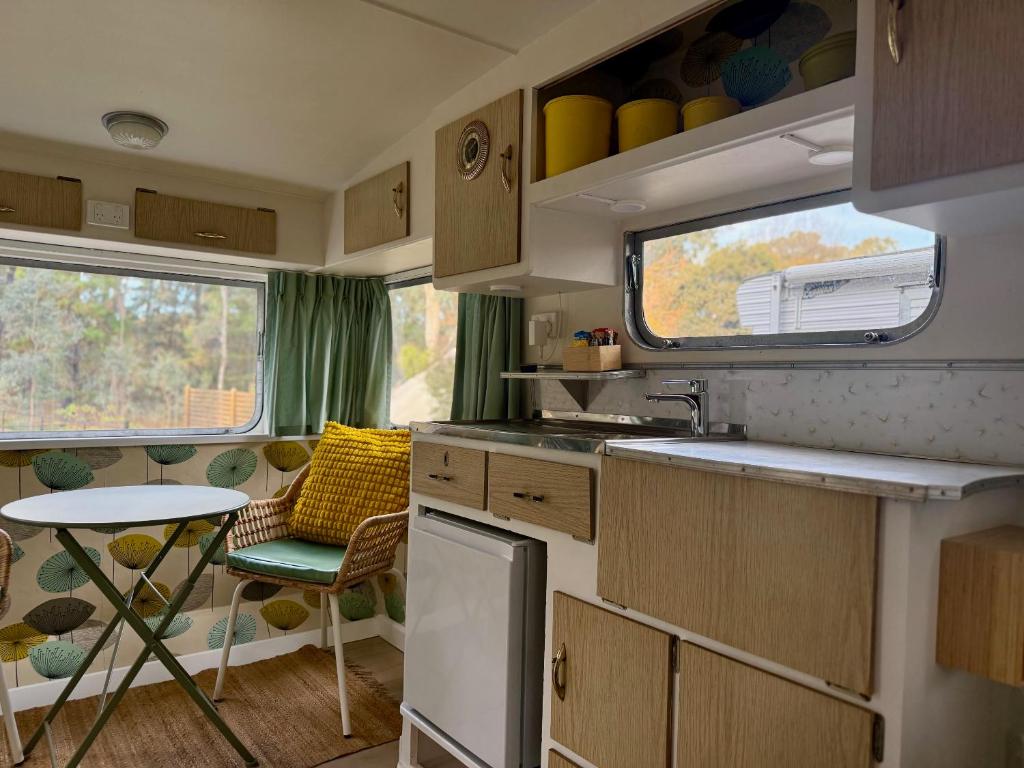 une cuisine avec un évier, une table et une fenêtre dans l'établissement Castlemaine Gardens Vintage 60's Caravan, à Castlemaine