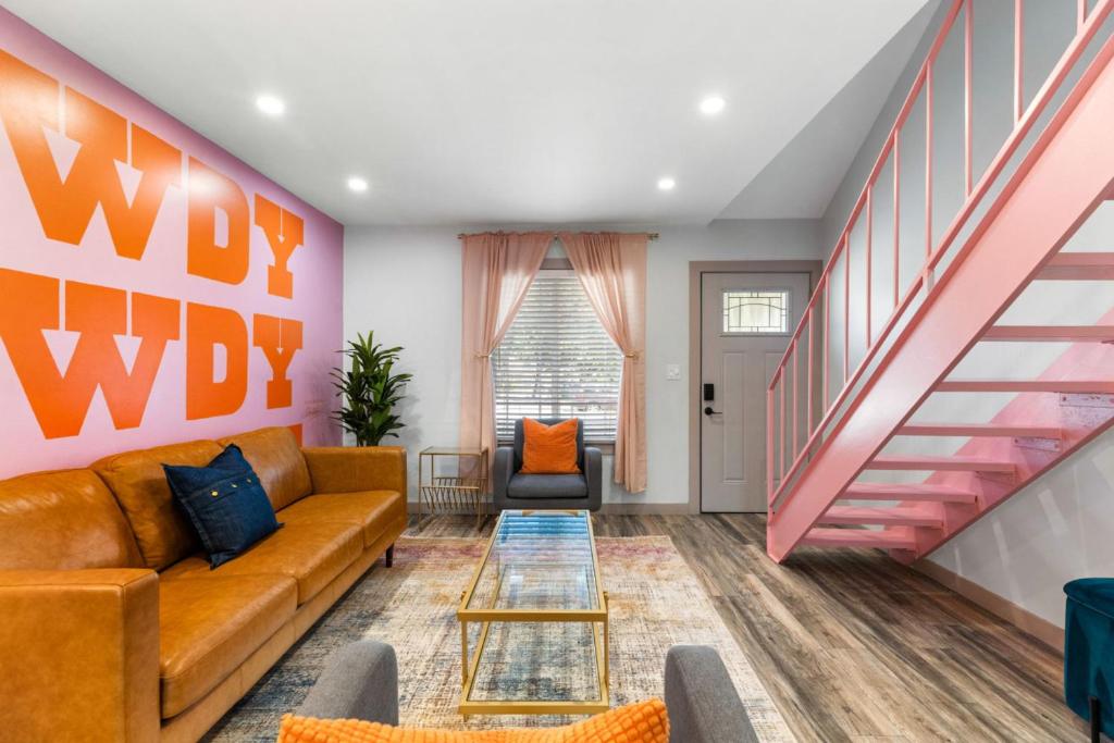 Una sala de estar con un sofá y una escalera. en Ladybird Pink Palace SoCo Dream Townhome!, en Austin