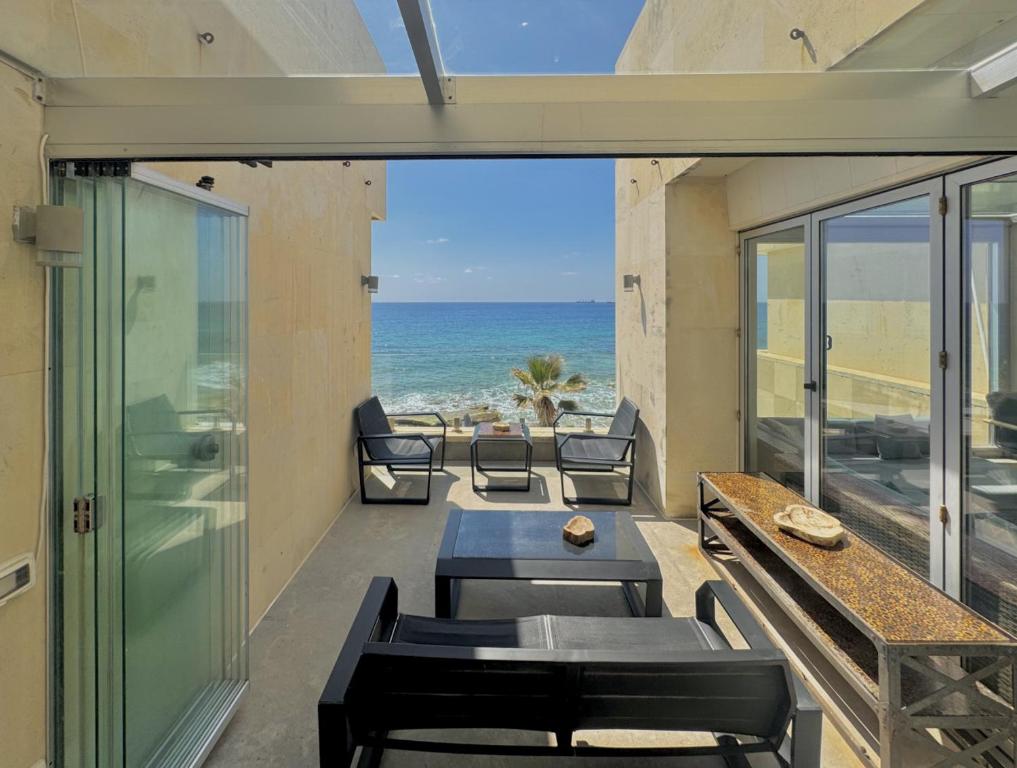 Un balcón con mesa y sillas y el mar. en Shatt El Reewa Villa, en Fad‘ūs