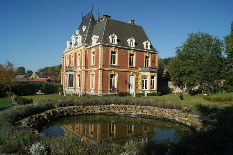 a large house with a pond in front of it at Chateau Neufays in Theux