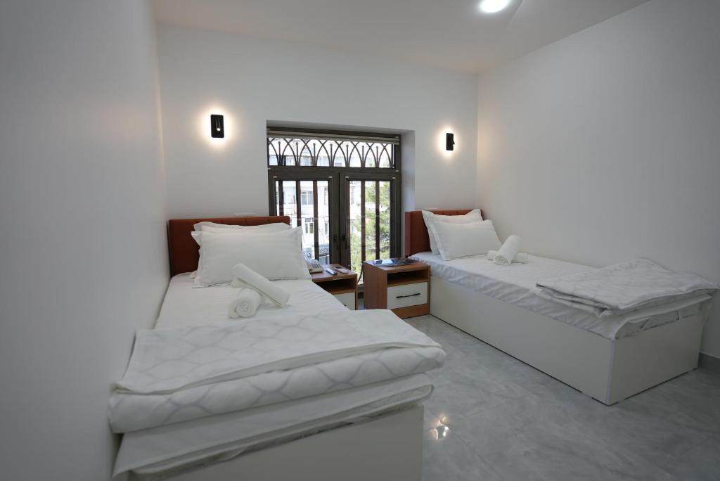 twee bedden in een kamer met een raam bij Kamilovs' Hotel in Tasjkent