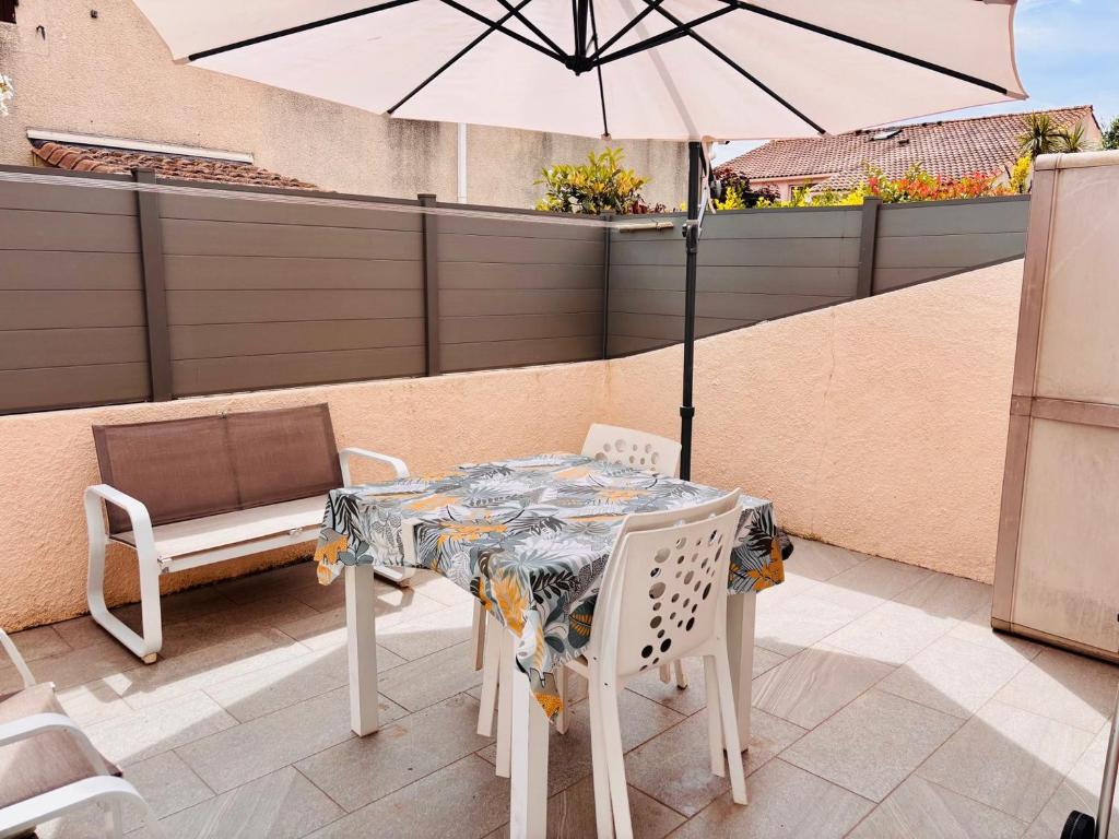 une table et des chaises avec un parasol sur une terrasse dans l'établissement Appt RDC tout confort Clim Parking Terrasse, à Argelès-sur-Mer