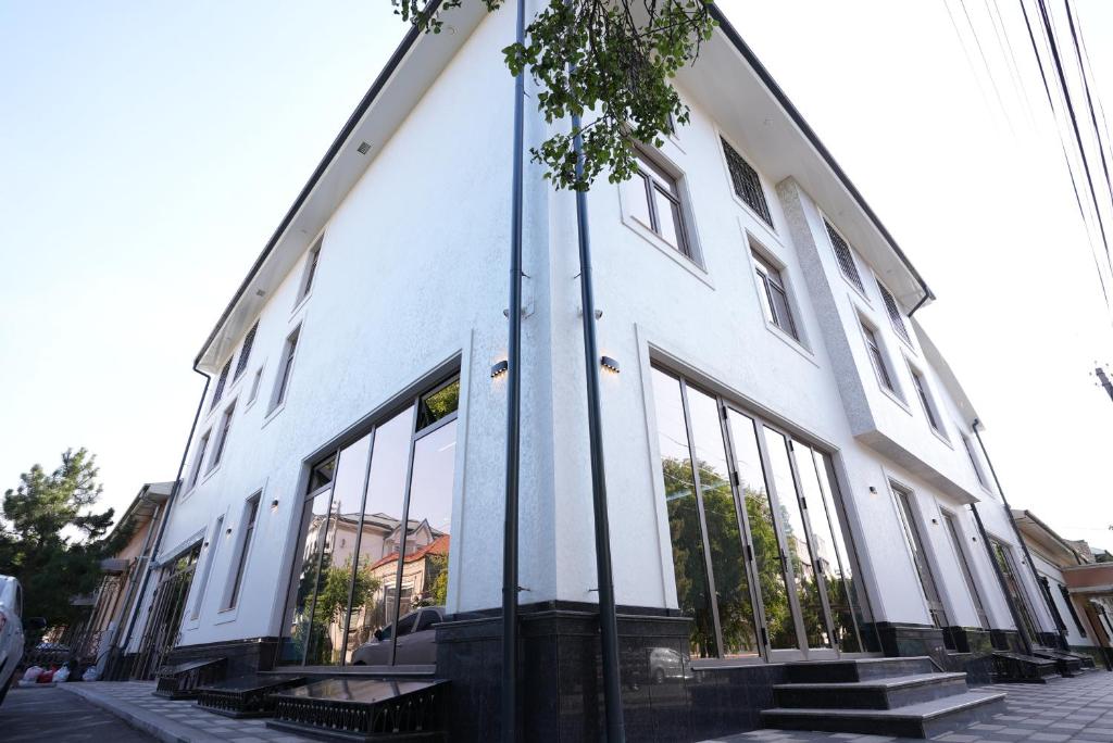 a white building with large windows on a street at Kamilovs' Hotel in Tashkent