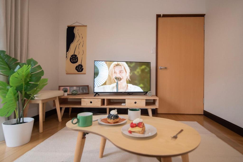ein Wohnzimmer mit Fernseher und einem Tisch mit Essen darauf in der Unterkunft Kaze Box in Kasaoka