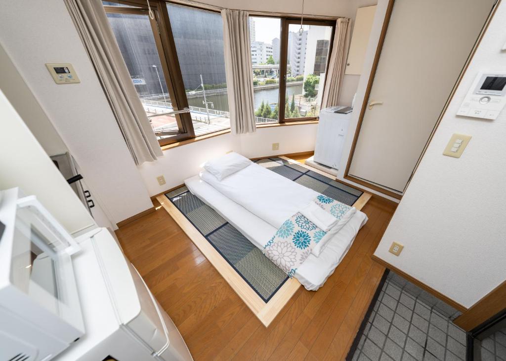 Una pequeña habitación con una cama y una ventana. en 匯金芝浦ビル, en Tokio