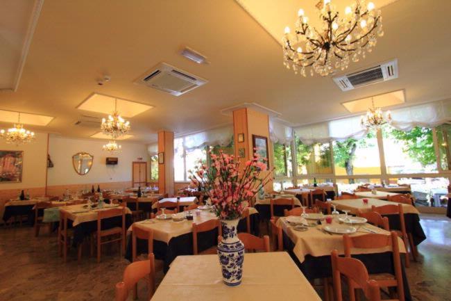 a dining room with tables and a vase of flowers at Hotel Moby Dick in Rimini